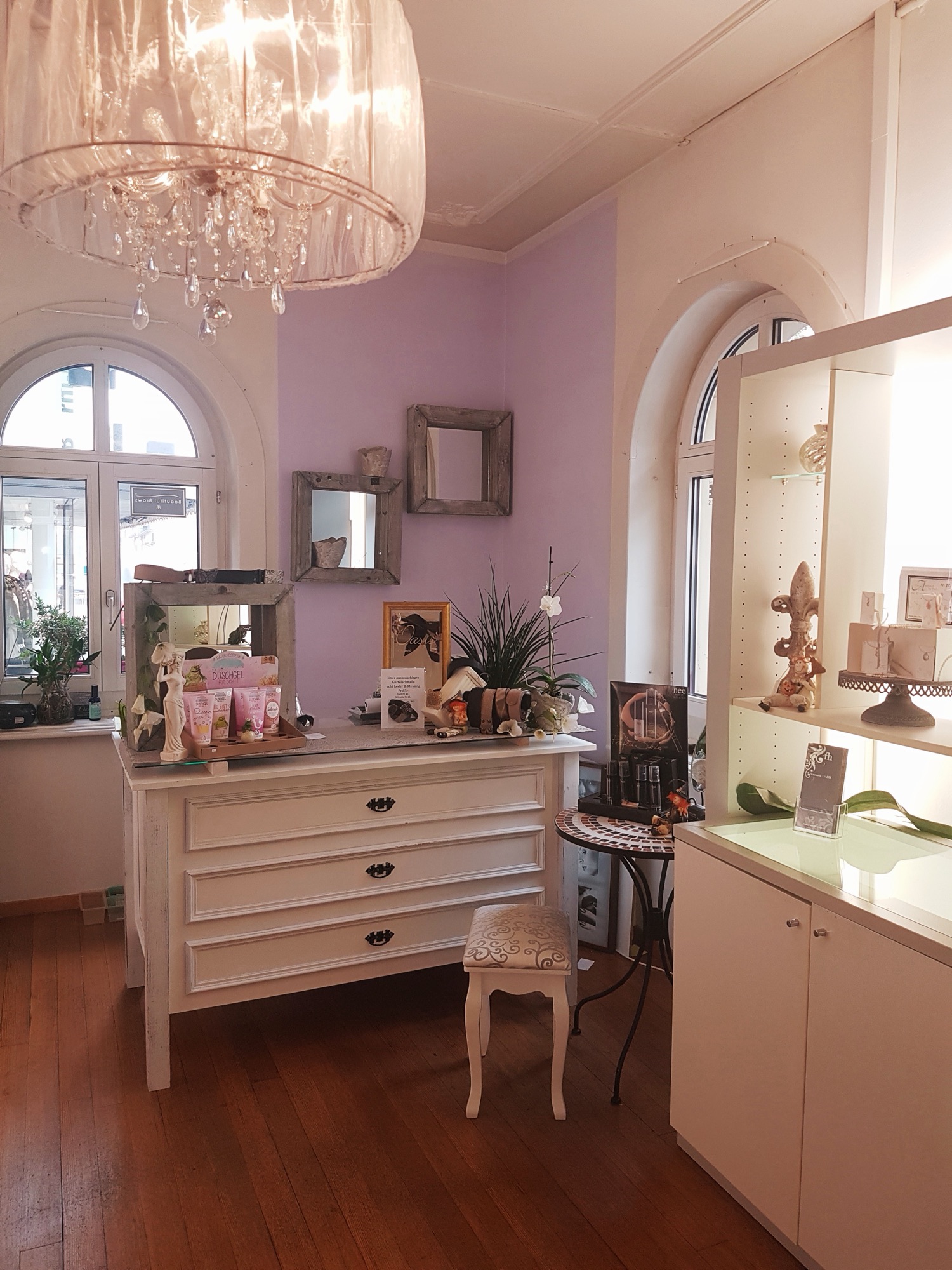 Das Studio von Cosmetic Oasis: Fliederwand, weisse Kommode, Kristall-Lüster und Bogenfenster